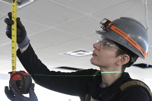Female electrician measuring ceiling