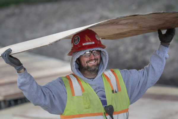 Union carpenter carrying plywood over his head