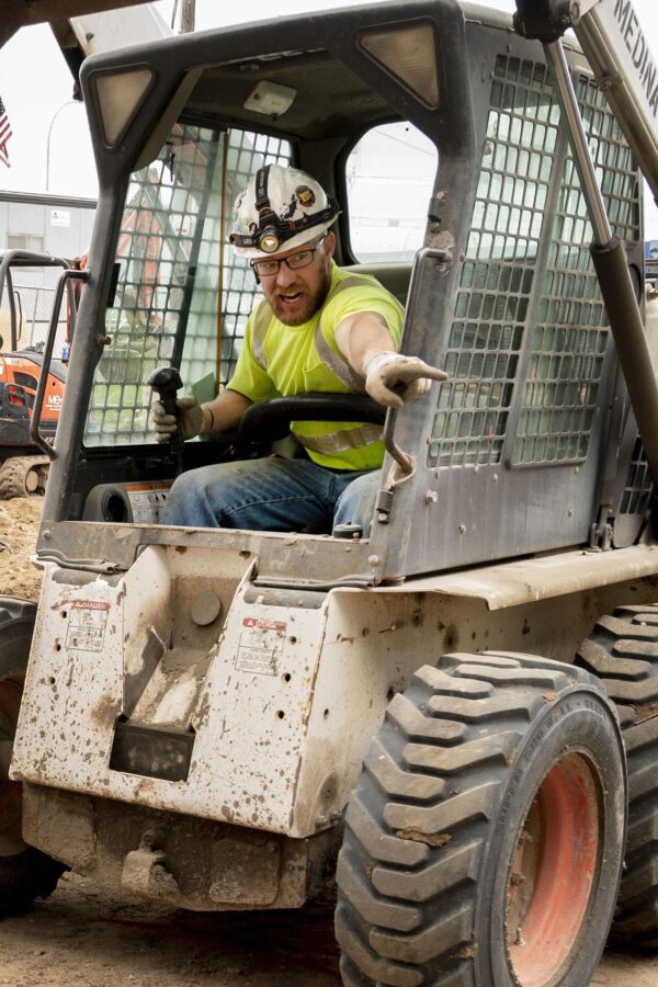 Operating Engineer driving a skid loader on construction site